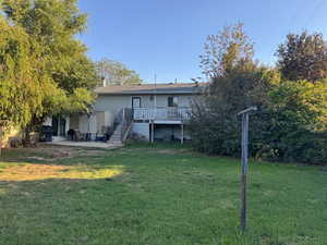 Rear view of property featuring a patio, a yard, and stairs