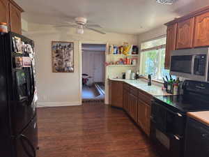 Kitchen with black appliances, light countertops, brown cabinets, and dark wood finished floors