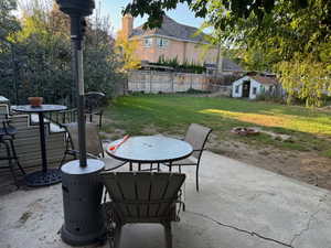 Fenced backyard with outdoor dining area, a patio, an outdoor fire pit, and a shed