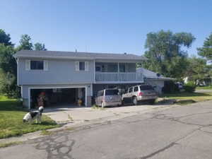View of front of house with a balcony, driveway, a garage, and a front yard