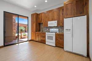 Kitchen with white appliances, brown cabinetry, tasteful backsplash, light wood-style flooring, and recessed lighting