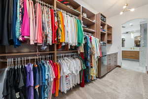 Walk in closet featuring light colored carpet and arched walkways