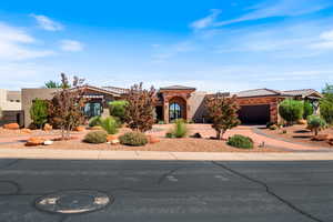 View of front of house with stucco siding, driveway, stone siding, an attached garage, and a tile roof