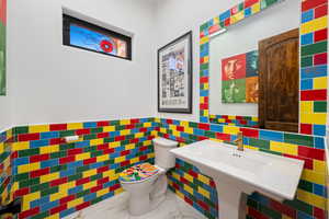 Half bathroom featuring tile walls and a wainscoted wall