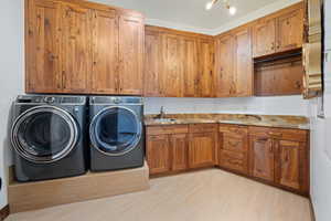 Laundry room featuring cabinet space, washing machine and clothes dryer, and light wood-style floors
