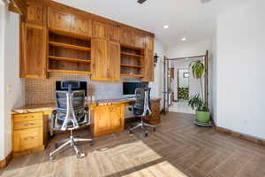 Office space with built in study area, recessed lighting, and parquet floors