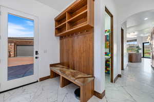 Mudroom featuring arched walkways and light marble finish floors