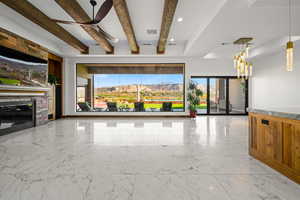 Unfurnished living room with light marble finish flooring, a mountain view, beamed ceiling, and a fireplace