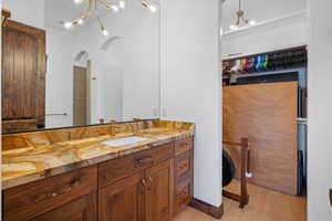 Bathroom featuring vanity, a chandelier, light wood-style floors, and a spacious closet
