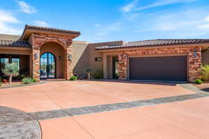 Mediterranean / spanish-style house featuring driveway, stone siding, stucco siding, an attached garage, and french doors