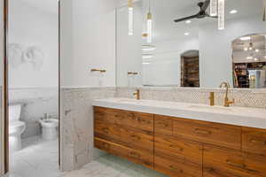 Full bath with a bidet, double vanity, recessed lighting, ceiling fan, and tile walls