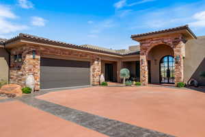 Mediterranean / spanish-style house with stone siding, concrete driveway, stucco siding, a garage, and a tile roof