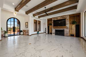 Unfurnished living room featuring arched walkways, light marble finish flooring, french doors, beam ceiling, and a large fireplace