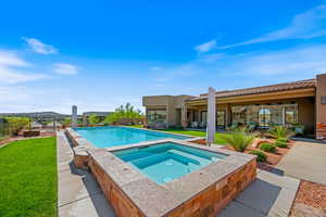 Outdoor pool featuring an in-ground hot tub, a patio area, and a yard