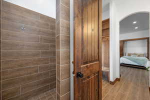 Ensuite bathroom featuring a shower stall, recessed lighting, and wood finish floors
