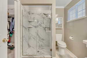 Bathroom featuring a marble finish shower, a walk in closet, and ornamental molding