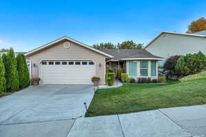 Ranch-style home featuring concrete driveway, a front lawn, an attached garage, and roof with shingles