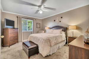 Bedroom with ornamental molding, light carpet, a ceiling fan, and a textured ceiling