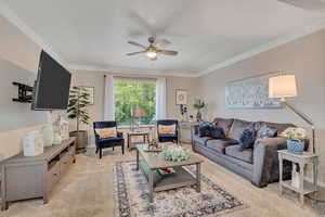 Living room with crown molding, light carpet, and ceiling fan