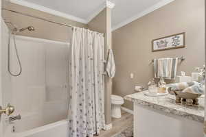 Bathroom with shower / bath combo with shower curtain, vanity, a textured ceiling, crown molding, and light wood-style flooring
