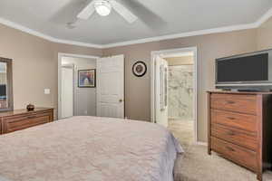 Bedroom featuring ornamental molding, light colored carpet, ceiling fan, ensuite bathroom, and a textured ceiling
