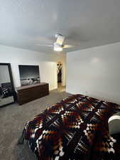 Bedroom with carpet floors, a textured ceiling, ceiling fan, and a spacious closet