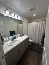 Full bath featuring vanity, dark wood-style flooring, a textured ceiling, a shower with curtain, and recessed lighting
