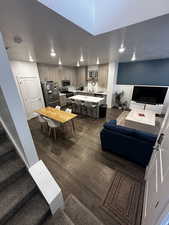 Living room with stairway, dark wood-type flooring, a textured ceiling, and recessed lighting