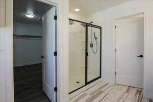Full bath featuring a stall shower, a walk in closet, and recessed lighting