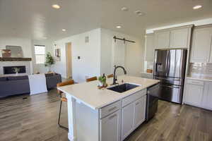 Kitchen with a kitchen breakfast bar, a barn door, appliances with stainless steel finishes, open floor plan, and a glass covered fireplace