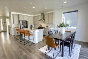 Kitchen featuring appliances with stainless steel finishes, gray cabinetry, a breakfast bar area, tasteful backsplash, and a center island with sink