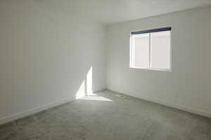 Carpeted spare room featuring baseboards