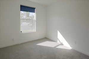 Carpeted spare room featuring baseboards