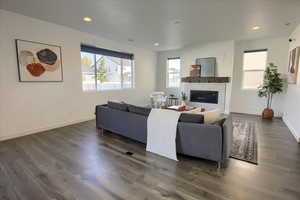 Living room featuring dark wood-type flooring, recessed lighting, and a glass covered fireplace