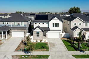 View of front facade with a residential view, stone siding, driveway, and an attached garage