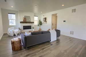 Living room with a glass covered fireplace, wood finished floors, and recessed lighting