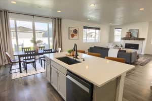 Kitchen featuring recessed lighting, dishwasher, open floor plan, dark wood-style floors, and a kitchen island with sink