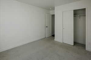 Unfurnished bedroom featuring light carpet and a closet