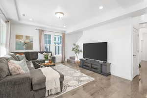 Living area featuring a tray ceiling, stairway, wood finished floors, and recessed lighting