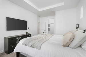 Bedroom featuring light colored carpet and a raised ceiling