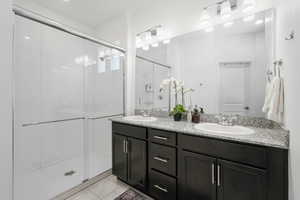 Full bathroom with light tile patterned floors, a shower stall, double vanity, and recessed lighting