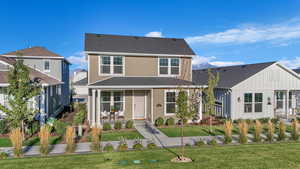 View of front facade featuring covered porch, a front lawn, and board and batten siding