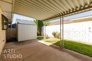 Fenced backyard featuring a storage unit and a patio