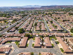 Aerial view of property and surrounding area featuring a mountainous background and nearby suburban area