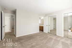 Unfurnished bedroom featuring light carpet, multiple closets, and ensuite bathroom