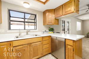 Kitchen featuring stainless steel dishwasher, light countertops, brown cabinets, and a peninsula