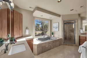 Full bath featuring a stall shower, a garden tub, two vanities, recessed lighting, and light tile patterned floors