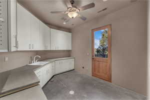 Kitchen featuring unfinished concrete floors, white cabinetry, a ceiling fan, and light countertops