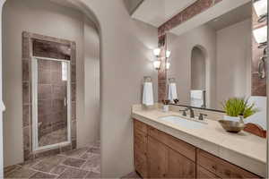 Full bath featuring vanity, a shower stall, and dark stone finish floors