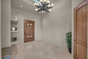 Foyer entrance with light tile patterned flooring, a chandelier, and recessed lighting